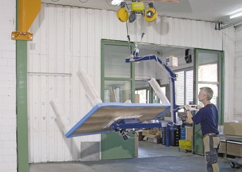 Slewing pillar crane with vacuum lifter lifts table
