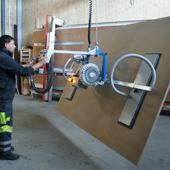 A large wooden panel is lifted by the forklift, tilted by 90° and moved to the vertical saw for cutting to size