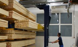 Regalbediengerät mit Hubgabel Holzbalken werden mit Kransystem in das Regal gehoben